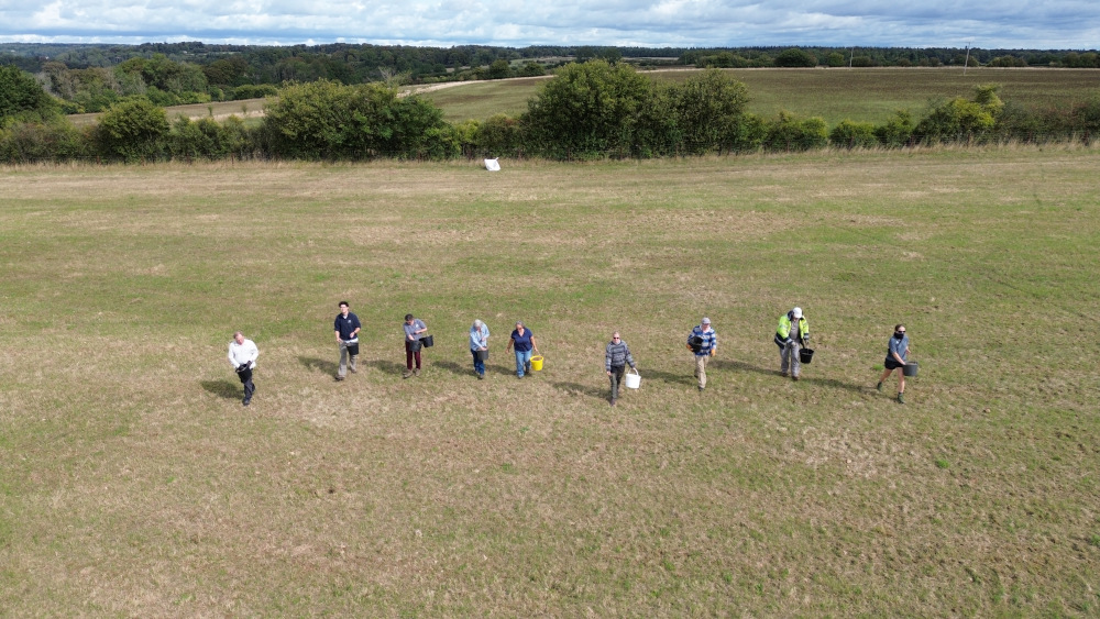 An aerial photo of a group of people sowing seed in a field
